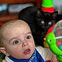 Colby is registered to the contest to win money with this photo: baby, infant, blue_bib, ravenclaw, toy, green_toy, black_cat, kitten, face, wide_eyes, curious, indoor, child, person, cute, expression, closeup, background_blur, furniture, home