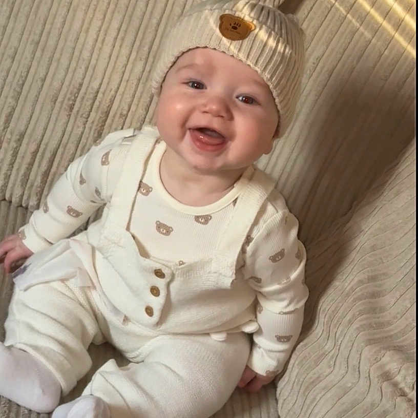 Roan is registered to the contest to win money with this photo: baby, child, couch, cozy, cute, cute_baby, fabric, face, happy, hat, indoor, infant, knitwear, portrait, sitting, smiling, teddy_bear, texture, warm, white_clothes