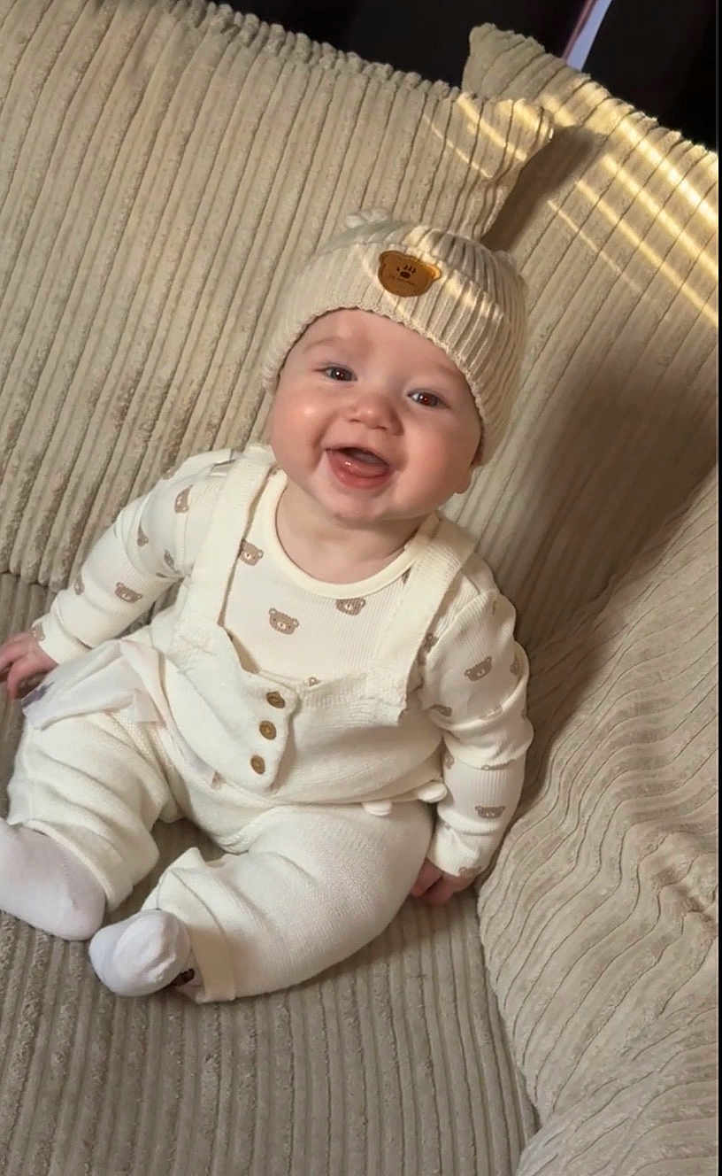 Roan is registered to the contest to win money with this photo: baby, child, couch, cozy, cute, cute_baby, fabric, face, happy, hat, indoor, infant, knitwear, portrait, sitting, smiling, teddy_bear, texture, warm, white_clothes