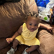 Daron Rampey is registered to the contest to win money with this photo: toddler, child, smile, yellow_outfit, braided_hair, beads, brown_couch, leather, silver_shoes, sitting, indoors, happy, person, furniture, home, casual, cute, playful, young_child, cozy