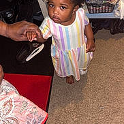 Daionna Rampey is registered to the contest to win money with this photo: toddler, child, person, hand, carpet, clothing, shoe, adult_hand, indoor, beads, hair, striped_dress, floor, furniture, basket, pillow, bottle, container, shelf, room