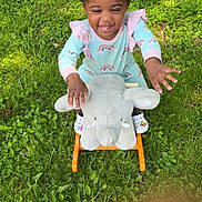 Daionna Lavai is registered to the contest to win money with this photo: child, toddler, grass, outdoor, toy, plush_elephant, rocking_toy, happy, smiling, colorful_hair_beads, greenery, play, cute, pastel_clothing, footwear, sunlight, nature, fun, joy, baby