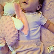 Elora joined the competition — help win amazing prizes! baby, plush_toy, blanket, infant, soft_toy, pink, lying_down, cute, child, face, person, toy, pacifier, clothing, indoors, comfort, young_child, smiling, happy, cozy