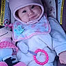 Elora is registered to the contest to win money with this photo: baby, infant, car_seat, hat, pink, bib, pacifier, blanket, plush_toy, smiling, cute, cozy, child, wearing_hat, warm_clothing, toy, indoor, face, person, seat
