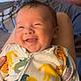 baby, smiling, child, onesie, animal_print, indoor, bedroom, pillow, blanket, happy, infant, cute, person, face, young_child, sleepwear, cozy, soft_lighting, portrait, comfort