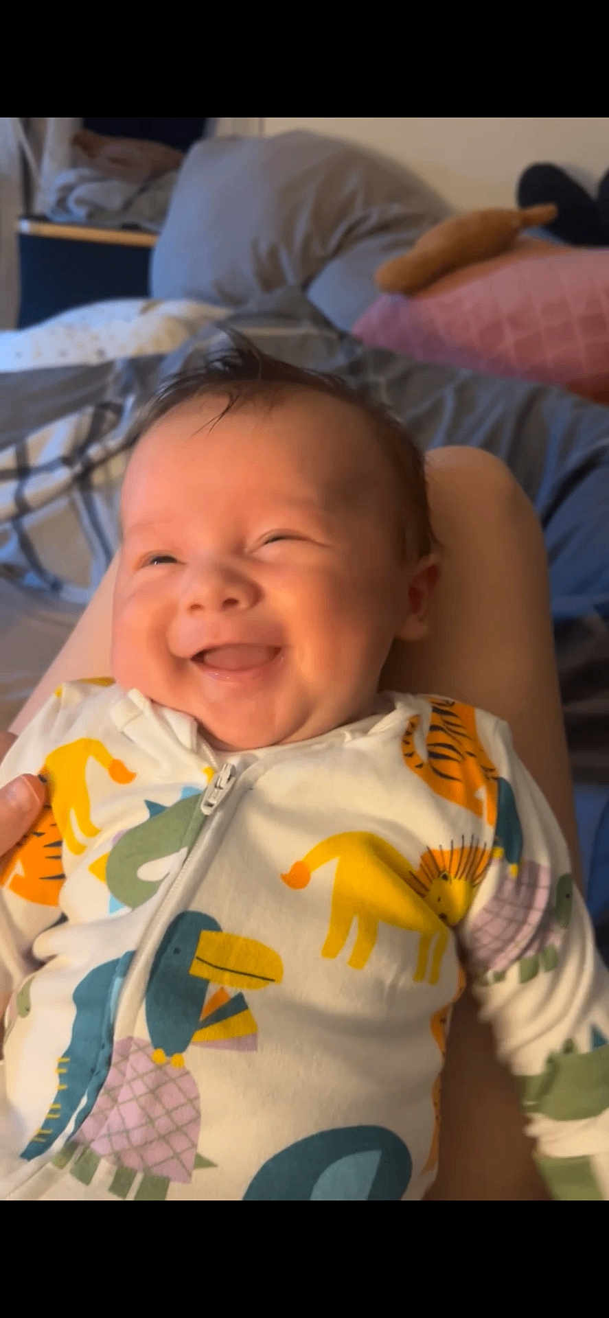 Luka joined the competition — help win amazing prizes! baby, smiling, child, onesie, animal_print, indoor, bedroom, pillow, blanket, happy, infant, cute, person, face, young_child, sleepwear, cozy, soft_lighting, portrait, comfort