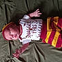 baby, casual, child, clothing, cute, expression, fabric, face, green_background, hat, indoors, infant, lying_down, newborn, onesie, person, portrait, small_hands, soft_light, striped_pants