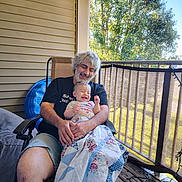 Jaythan joined the competition — help win amazing prizes! adult, baby, blanket, chair, clothing, daylight, fence, flower_pattern, happy, human, laughter, nature, outdoor, person, porch, quilt, relaxation, smile, tree, wood