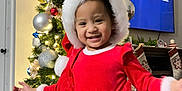 Liora Zorel joined the competition — help win amazing prizes! celebration, child, christmas_tree, cute, decorations, festive_clothing, happy, holiday, holiday_spirit, indoor, lights, living_room, ornaments, person, presents, red_dress, seasonal, smiling, toddler, white_fur