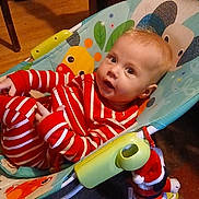 Larry is registered to the contest to win money with this photo: baby, infant, child, striped_pajamas, bouncer, baby_seat, surprised_expression, wide_eyes, indoor, wooden_floor, toy, stuffed_santa, red_white, portrait, head, face, hands, cozy, home, smile