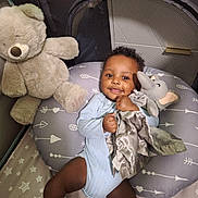 Sohan joined the competition — help win amazing prizes! baby, child, infant, teddy_bear, plush_toy, elephant_toy, pillow, bedding, stars_pattern, smiling, cute, indoor, person, sleeping_area, baby_clothing, baby_girl, baby_boy, resting, happy, cozy