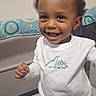 toddler, child, smiling, happy, indoor, playpen, white_shirt, dinosaur_print, baby, cute, portrait, person, standing, young_child, clothing, home, infant, face, joyful, curious