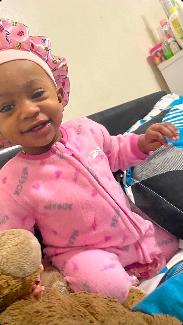 A'Mora is registered to the contest to win money with this photo: baby, baby_toddler_clothing, cap, child, comfort, event, fashion_accessory, fun, happy, lap, leisure, magenta, person, pink, room, sitting, skin, smile, stuffed_toy, teddy_bear