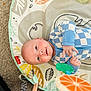 baby, infant, child, lying_down, play_mat, toy, blue_clothing, checkered_pattern, happy, smiling, face, hand, carpet, indoor, cute, young_child, light_skin, head, eyes, playtime