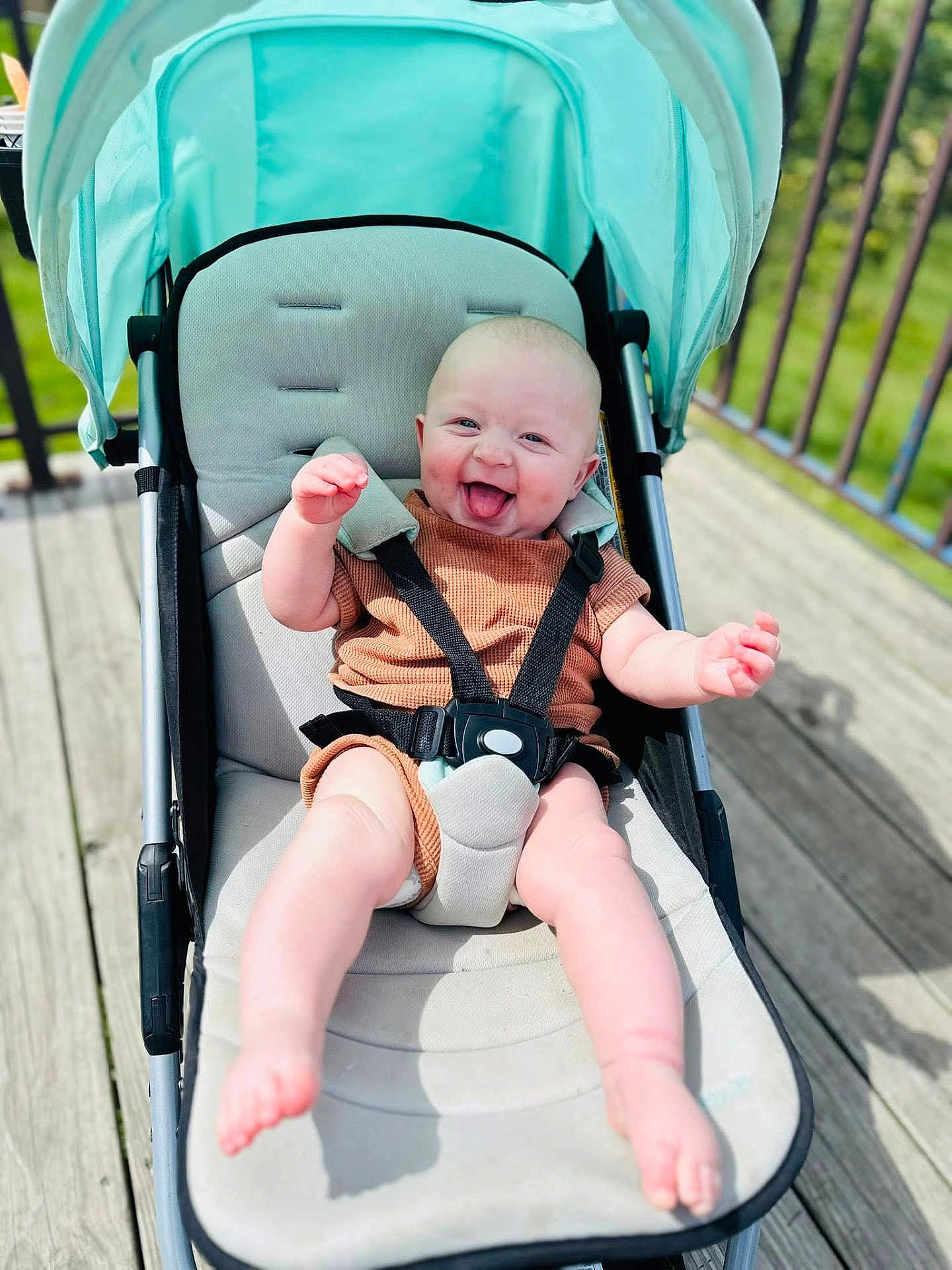 Beckham joined the competition — help win amazing prizes! baby, stroller, smiling, tongue_out, outdoor, sunny, wooden_deck, baby_clothing, happy, infant, child, seatbelt, canopy, person, cute, playful, summer, baby_girl, baby_boy, daylight