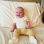 Beckham is registered to the contest to win money with this photo: baby, smiling, sitting, bed, pillow, blanket, clothing, socks, happy, infant, person, cute, indoors, portrait, young_child, head, face, skin, comfort, cozy