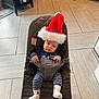 Tucker is registered to the contest to win money with this photo: appliance, baby, babybjorn, bouncer, cabinet, child, christmas, cute, floor, furniture, holiday, indoor, infant, kitchen, portrait, santa_hat, socks, striped_pants, tile_floor, wine_bottles