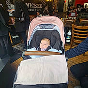 Presley is registered to the contest to win money with this photo: baby, baby_carriage, bottle, casual, chair, clothing, floor, food, hand, indoor, lighting, menu, people, person, restaurant, seated, stroller, table, wall_art, wood_floor