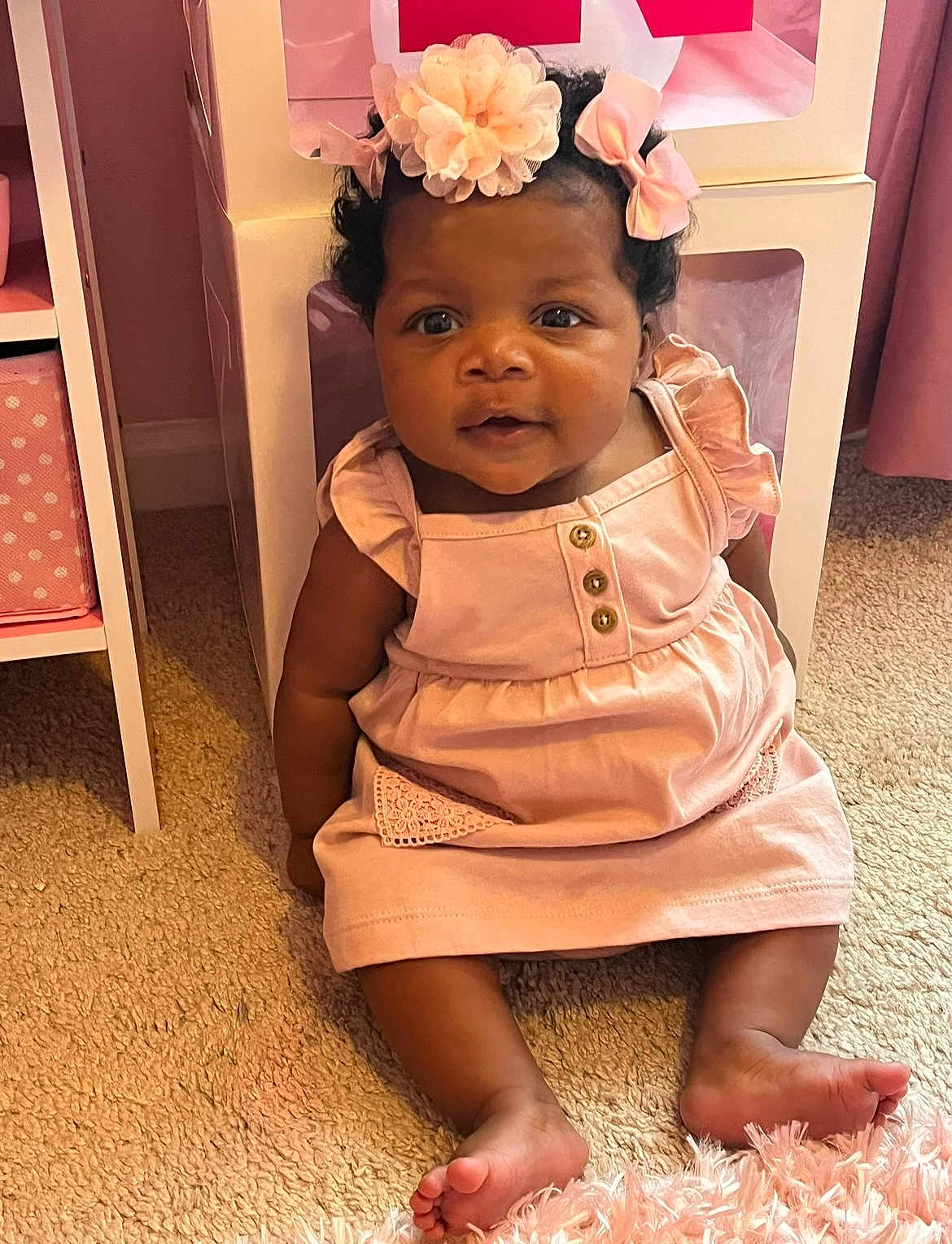 Mckenzie is registered to the contest to win money with this photo: baby, child, infant, pink_dress, headband, flower, carpet, furniture, indoors, cute, smiling, sitting, skin, foot, room, decor, person, portrait, young, adorable