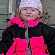 Mariana joined the competition — help win amazing prizes! toddler, child, pink_hat, pom_pom, snowsuit, pacifier, cat, door, outdoor, winter_clothing, portrait, smiling, face, cold_weather, seated, animal, pet, cozy, young_child, casual