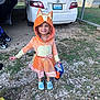 child, costume, fox, orange, halloween, bucket, toyota, car, camry, gravel, grass, stroller, carport, smile, outdoor, footwear, hood, dress, daylight, cute