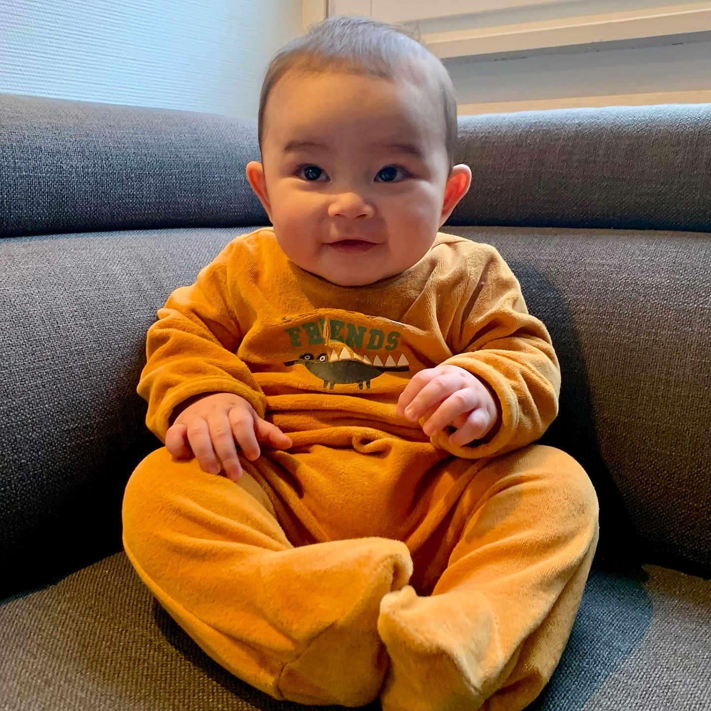 Milan participe au concours pour gagner de l'argent avec cette photo : baby, bodypart, clothing, couch, cushion, face, finger, furniture, hand, happy, head, homedecor, indoors, pajamas, pants, person, photography, portrait, sitting, smile