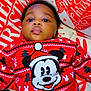 baby, child, mickey_mouse, red_sweater, christmas, holiday, pillow, face, portrait, cute, infant, smiling, lying_down, indoors, festive, clothing, young_child, holiday_season, cozy, bright_colors