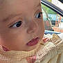 baby, close_up, face, child, curious, clothing, floral_pattern, soft_texture, indoors, car_window, portrait, young, cute, skin, eyelashes, nostrils, lips, head, infant, natural_light