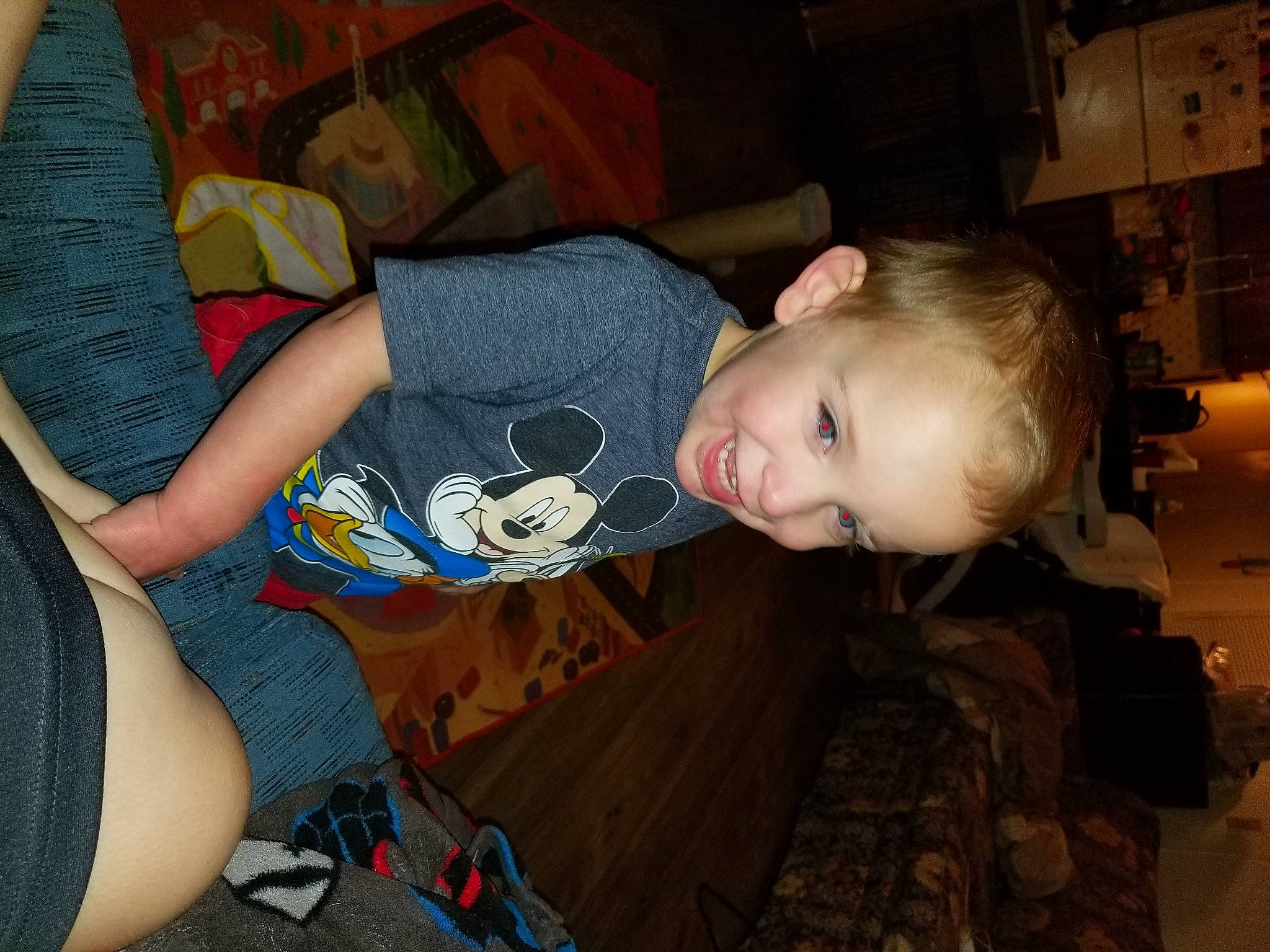 Liam is registered to the contest to win money with this photo: cheek, child, comfort, elbow, flooring, fun, hairstyle, human_body, human_leg, joy, knee, lap, military_camouflage, mouth, person, sitting, sleeve, smile, t_shirt, thigh