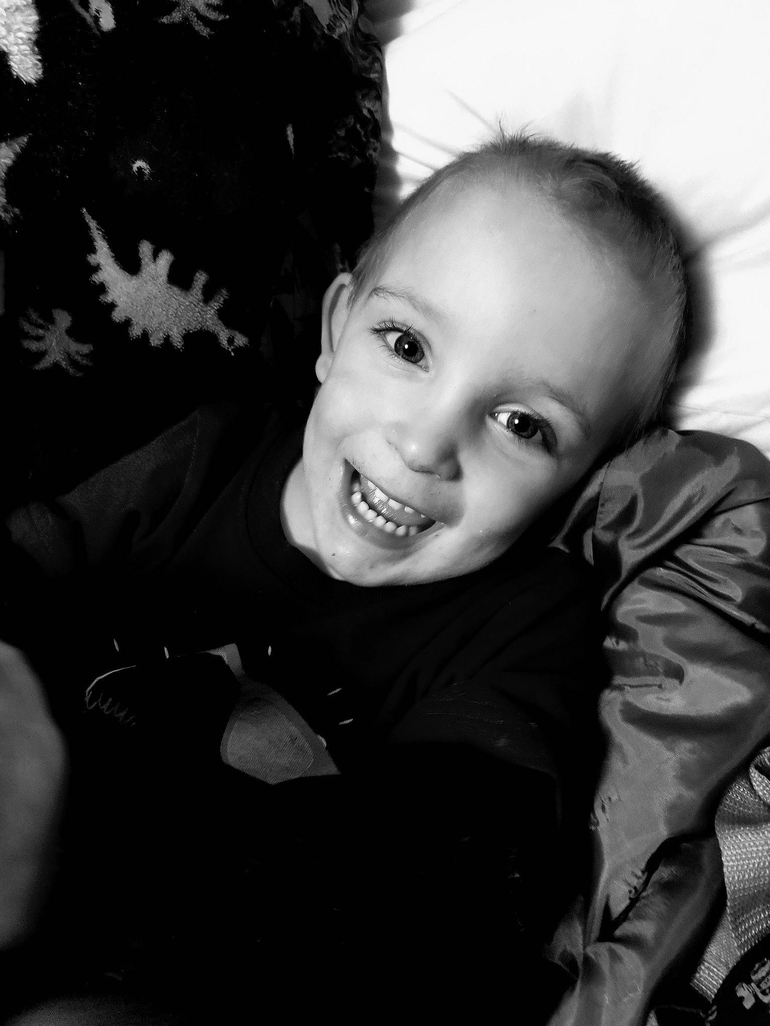 Liam is registered to the contest to win money with this photo: black_and_white, cheek, child, flash_photography, fun, fur, grass, happy, iris, joy, laugh, monochrome, monochrome_photography, person, portrait_photography, sitting, smile, standing, stock_photography, style