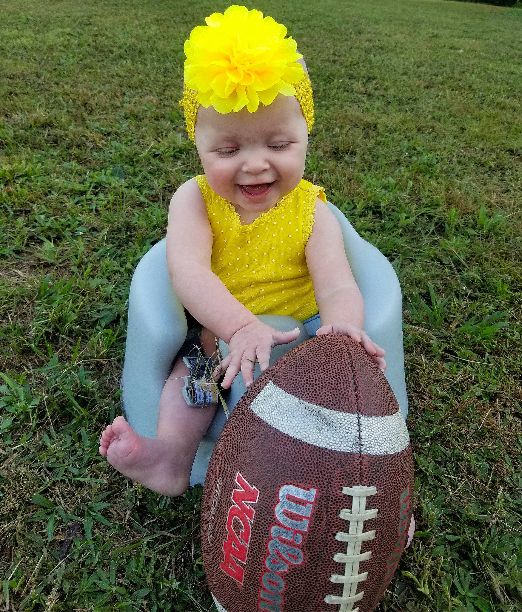 Nova is registered to the contest to win money with this photo: baby, baby_toddler_clothing, ball, child, face, facial_expression, flower, football, grass, grass_family, happy, headgear, headpiece, headwear, people_in_nature, person, personal_protective_equipment, petal, pink, plant