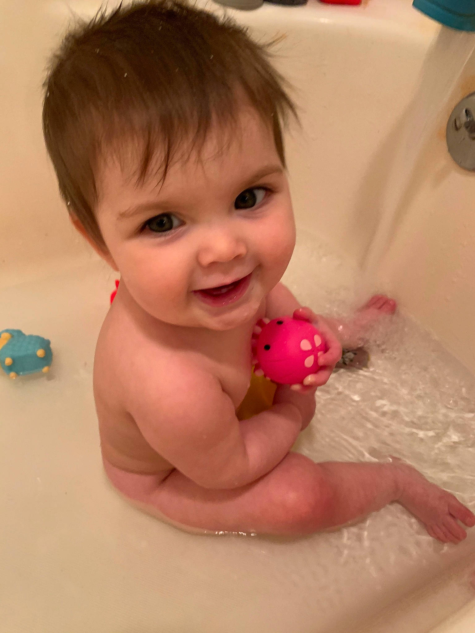 Scarlett is registered to the contest to win money with this photo: baby, baby_bathing, bathing, bathtub, cheek, child, face, fun, head, person, pink, product, room, skin, smile, toddler, toy