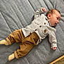 Ilyane participe au concours pour gagner de l'argent avec cette photo : baby, infant, child, bed, mattress, clothing, grey_shirt, brown_pants, socks, fuzzy_slippers, carpet, indoor, person, laying_down, cute, small, head, face, legs, home