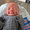 baby, newborn, infant, child, portrait, smiling, sleeping, eyes_closed, striped_clothing, onesie, blanket, reclining, indoor, home, cozy, face, head, close_up, colorful_blanket, photography