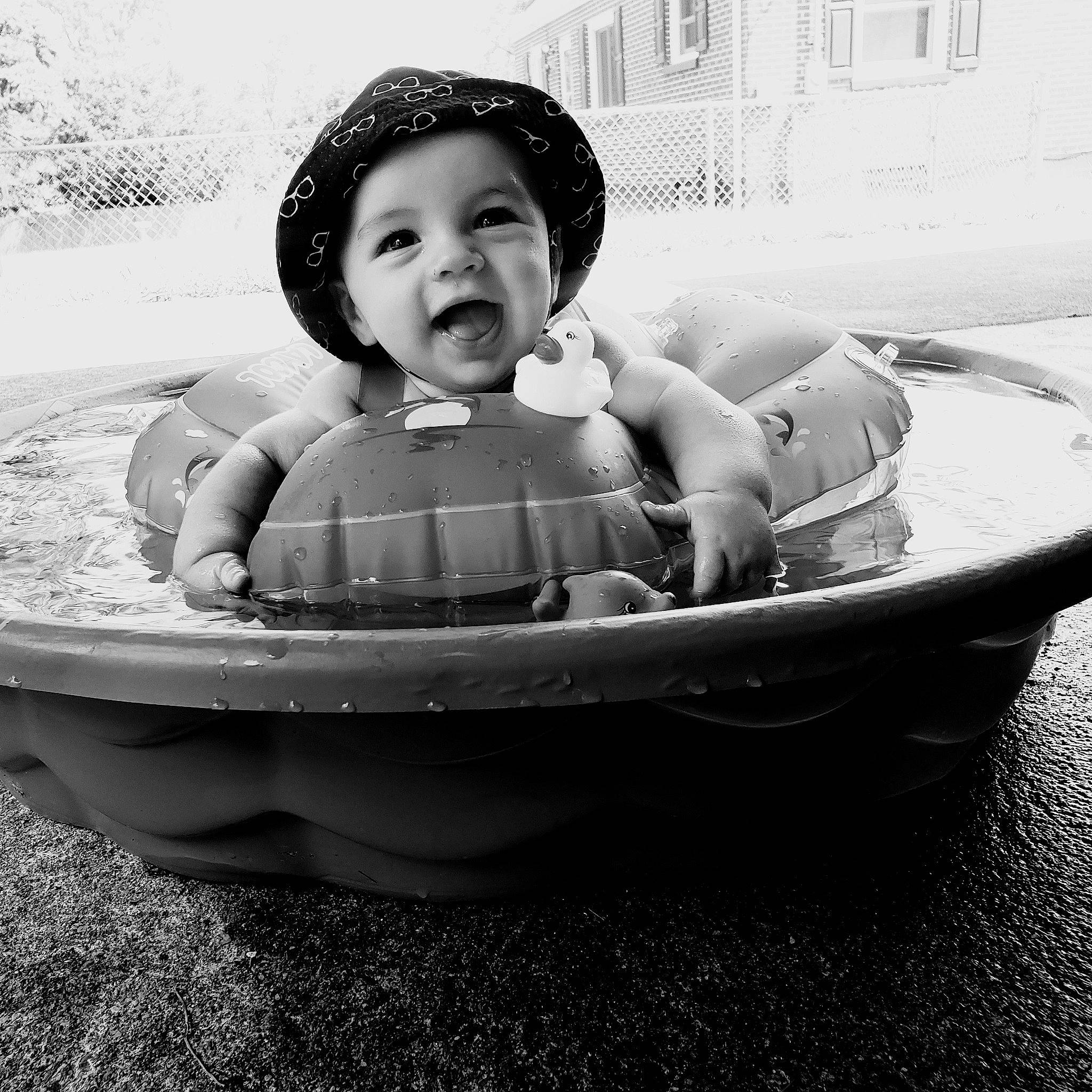 Leonidas is registered to the contest to win money with this photo: baby, baby_products, baby_toddler_clothing, black_and_white, boat, child, flash_photography, fun, grass, happy, monochrome, monochrome_photography, person, portrait_photography, recreation, sitting, smile, style, toddler, water