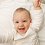 baby, smiling, happy, child, infant, white_clothing, blanket, soft_texture, cute, portrait, reaching_hand, light_skin, indoor, closeup, expressive_face, teeth, young_child, candid, joy, innocence