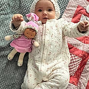 Hélya participe au concours pour gagner de l'argent avec cette photo : baby, child, doll, blanket, quilt, onesie, hat, toy, infant, soft, cute, lying_down, pink, white, patterned, fabric, nursery, indoor, person, smiling