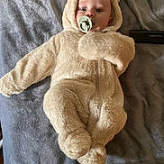 Aiden is registered to the contest to win money with this photo: baby, baby_boy, bear_costume, blanket, child, clothing, cozy, cute, expression, face, fur, headwear, indoors, infant, lying_down, onesie, pacifier, person, sleepwear, soft_texture