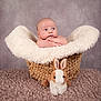 Aiden is registered to the contest to win money with this photo: baby, infant, basket, blanket, plush_toy, stuffed_animal, bunny, soft_texture, fur, portrait, cute, child, indoor, studio, cozy, resting, looking_away, woven, background, floor_covering