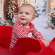 Freddie is registered to the contest to win money with this photo: baby, blue_eyes, celebration, child, christmas_theme, cute, decorations, festive, festivity, happy, holiday_lights, indoor, portrait, red_sleigh, seasonal, smiling, snow, striped_clothing, toddler, winter