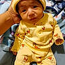 baby, infant, yellow_clothing, winnie_the_pooh, hat, hand, blanket, blue_blanket, cartoon_pattern, cute, child, portrait, indoors, soft_toys, smiling, sitting, cozy, warm_clothing, person, newborn