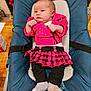 baby, infant, child, pink_jacket, plaid_skirt, black_leggings, gray_socks, baby_seat, blue_cushion, indoor, wooden_table, curious_expression, clothing, seated, small_hands, cute, young_child, face, person, portrait