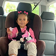 Alani is registered to the contest to win money with this photo: toddler, child, car_seat, seatbelt, pink_bows, pacifier, plush_toy, minnie_mouse, pink_shirt, beige_pants, white_sneakers, car_interior, window, headrest, safety, smiling, cute, young_child, hair_bows, child_safety