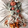 baby, newborn, infant, headband, bow, swaddle, blanket, bed, sleeping, hands, outfit, buttons, plush_toy, slippers, animal_slippers, floral_print, ruffles, cozy, portrait, cute
