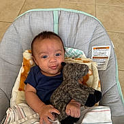 Sebastian joined the competition — help win amazing prizes! baby, infant, stuffed_animal, blanket, baby_chair, tiled_floor, indoor, cute, child, smiling, holding, soft_toy, comfort, seated, blue_clothing, portrait, young, person, happy, cozy