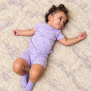 Aylanis joined the competition — help win amazing prizes! baby, child, infant, portrait, lying_down, smiling, happy, curly_hair, purple_clothing, romper, socks, rug, carpet, indoor, overhead_view, close_up, arms_outstretched, holding_object, soft_lighting, adorable