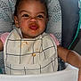 toddler, child, high_chair, bib, food_stains, messy_face, pucker, expression, pink_shirt, curly_hair, indoor, feeding_time, cute, smile, face, person, seat, baby, young_child, feeding