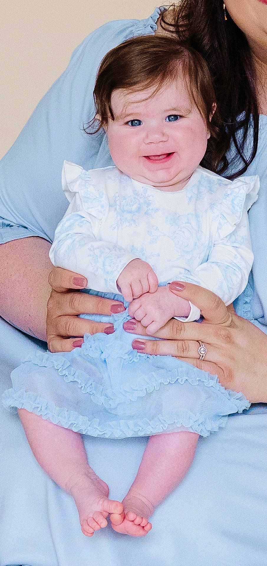 Ellie joined the competition — help win amazing prizes! adult_hands, baby, blue_dress, blue_eyes, child, closeup, clothing, cute, hands, happy, holding, infant, nail_polish, person, portrait, ring, ruffles, sitting, skin, smiling