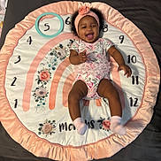 Brilani is registered to the contest to win money with this photo: baby, infant, smiling, laughing, headband, onesie, pink, white, milestone_blanket, months, floral, flower, soft, cute, child, happy, lying_down, playful, pastel, fabric