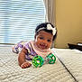 baby, child, smiling, toy, bed, blanket, headband, curtains, window, indoor, quilted, clothing, person, happy, infant, pajamas, face, hand, play, crawling